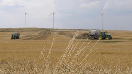 Ackerflächen mit Traktoren und Windenergieanlagen