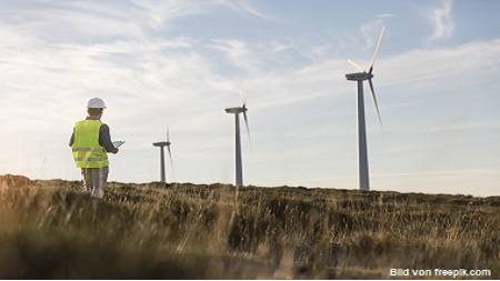 Windräder in der Landschaft, im Vordergrund Techniker von Windenergieanlagen